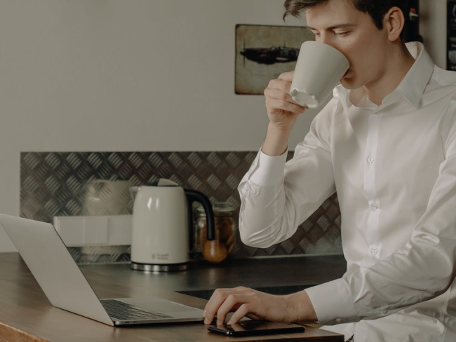 man in white dress shirt holding white ceramic mug and can work from home